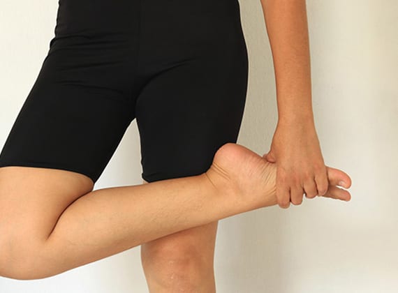 Woman holding foot due to inner pain above the arch from accessory navicular syndrome.