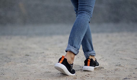 Woman with flat feet walking on beach.