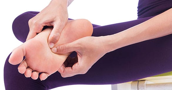 Woman with foot pain at the bottom of her feet because of tendonitis.